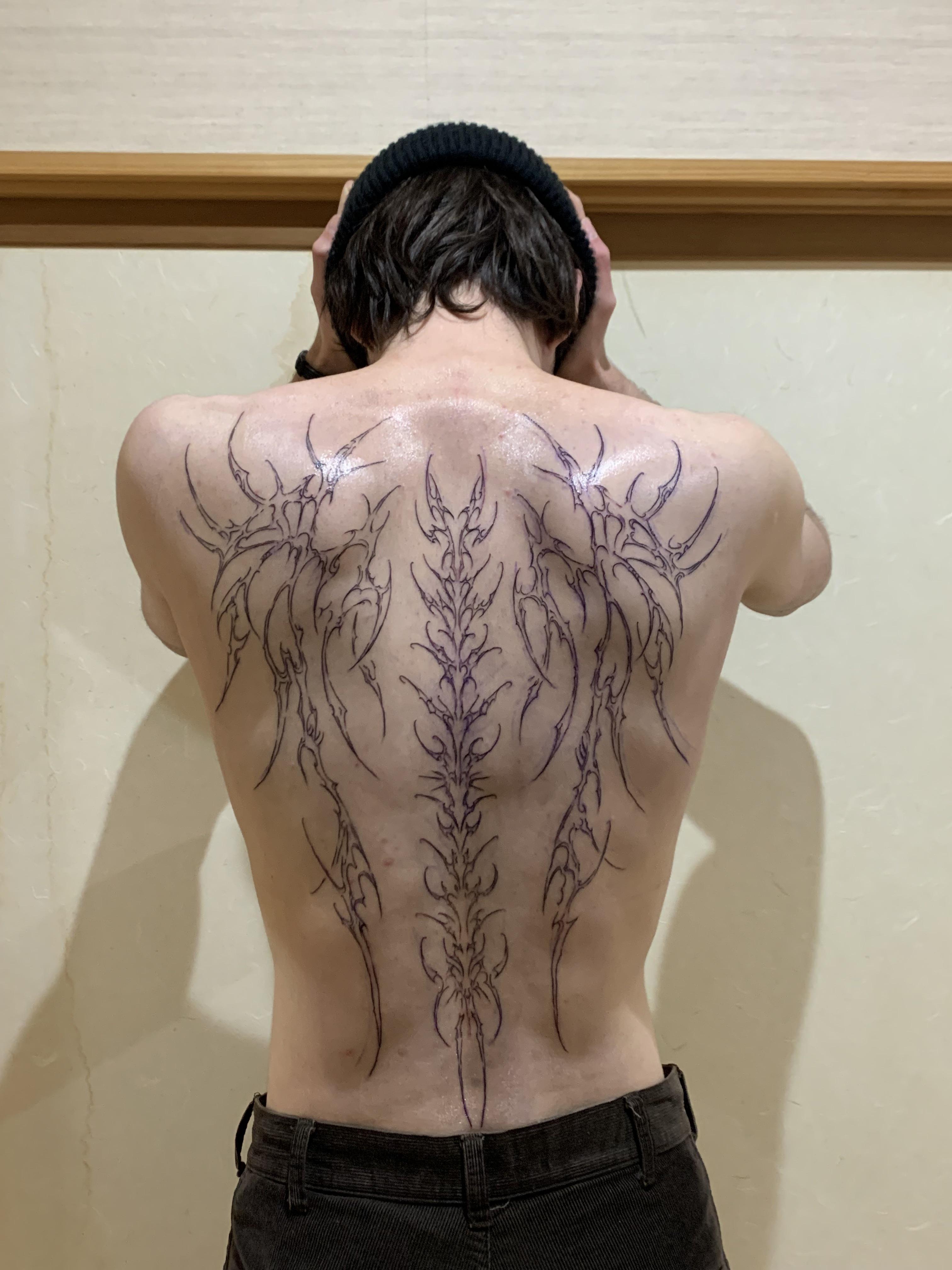 someone with a large cybersigil angel pattern tattoo showing their back